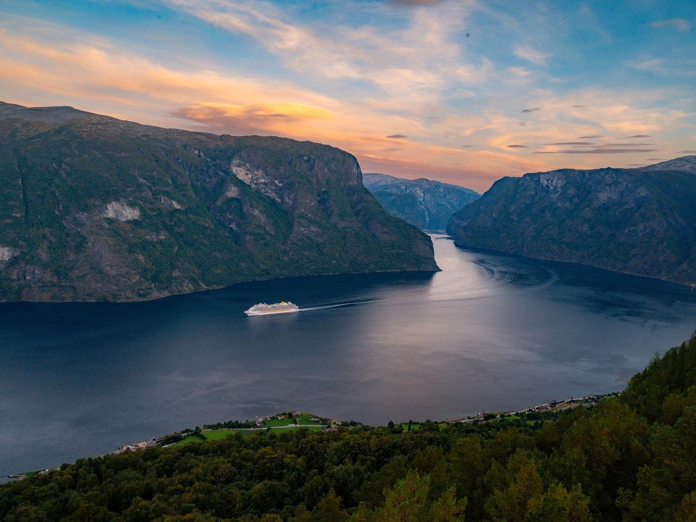 Fiorde norueguês ao entardecer com navio ao longe